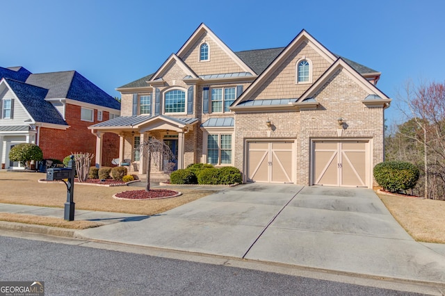 view of front of house with brick siding, metal roof, a garage, driveway, and a standing seam roof