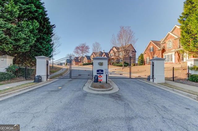 view of street with a gate, sidewalks, and a gated entry