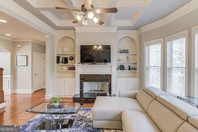 living room with a ceiling fan, baseboards, coffered ceiling, a high end fireplace, and light wood-style floors