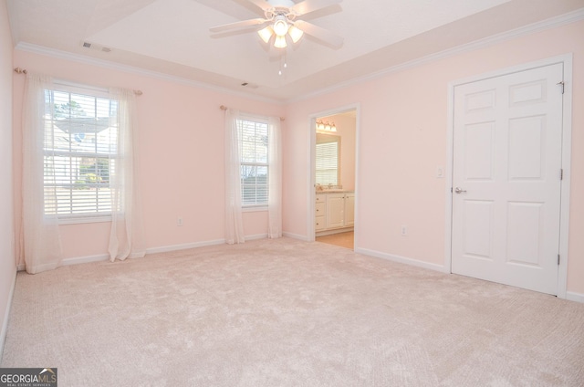 unfurnished bedroom with a tray ceiling, multiple windows, visible vents, and light carpet