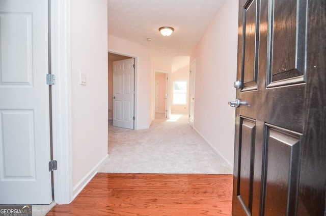 hallway with baseboards and light carpet