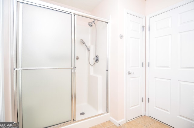 bathroom with baseboards, tile patterned flooring, and a stall shower