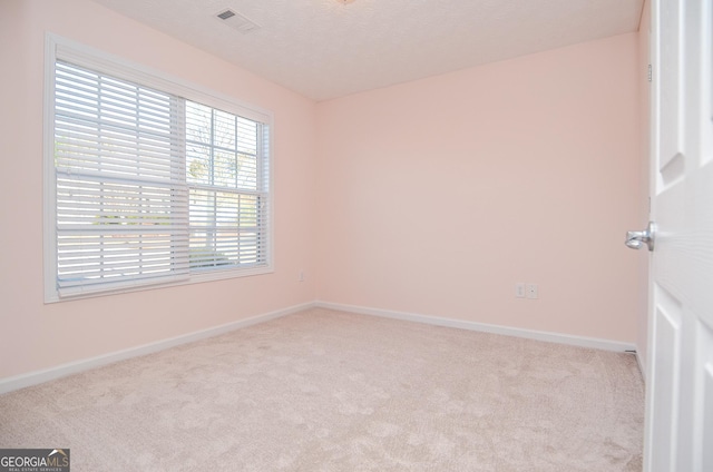 carpeted empty room featuring baseboards, visible vents, and a textured ceiling