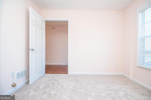 carpeted empty room with visible vents and baseboards