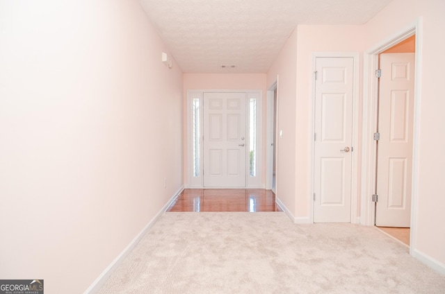 foyer featuring a textured ceiling, baseboards, visible vents, and carpet