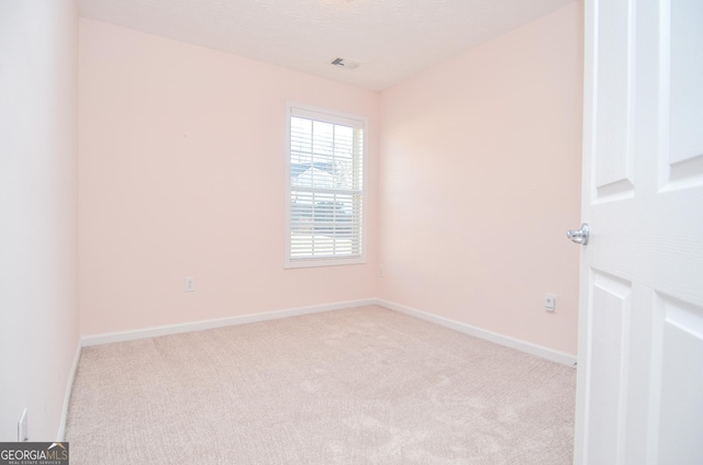 empty room featuring carpet flooring, visible vents, a textured ceiling, and baseboards