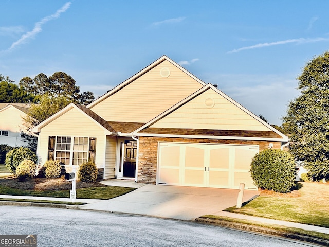 view of front facade featuring a shingled roof, concrete driveway, a front yard, and stone siding
