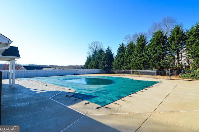 community pool with a patio area and fence