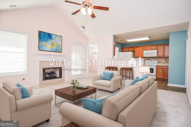 living room featuring a premium fireplace, visible vents, high vaulted ceiling, and ceiling fan