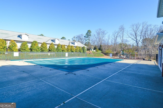 view of tennis court featuring a patio, a community pool, and fence