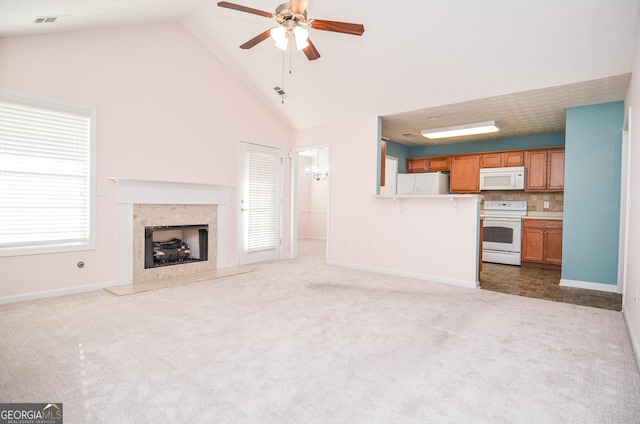 unfurnished living room with dark carpet, baseboards, high vaulted ceiling, a high end fireplace, and a ceiling fan