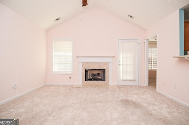 unfurnished living room featuring carpet flooring, ceiling fan, vaulted ceiling, a high end fireplace, and visible vents