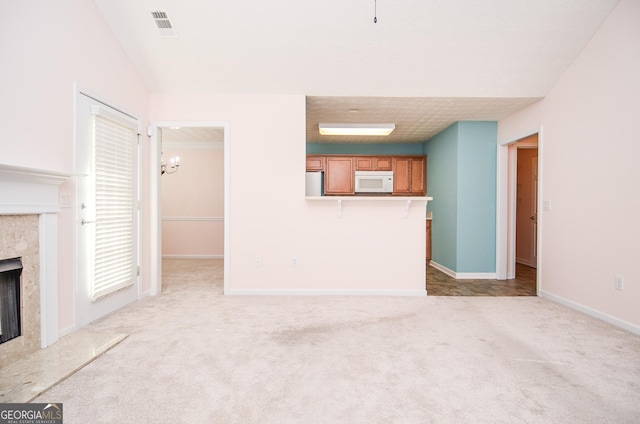 unfurnished living room featuring light colored carpet, baseboards, visible vents, and a high end fireplace