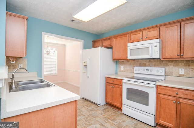 kitchen featuring visible vents, a sink, white appliances, and light countertops