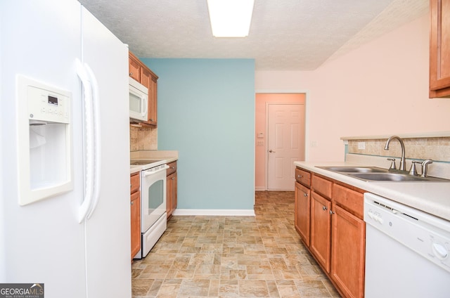 kitchen featuring light countertops, decorative backsplash, stone finish floor, white appliances, and a sink