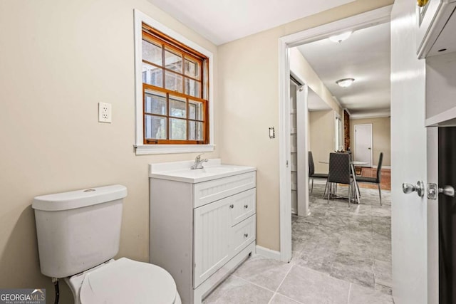 bathroom with baseboards, toilet, and vanity