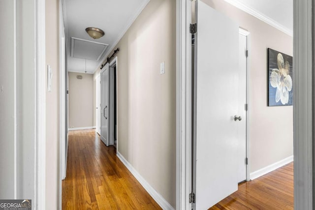 hallway with attic access, crown molding, wood finished floors, and baseboards