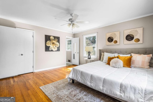 bedroom featuring ceiling fan, crown molding, baseboards, and wood finished floors