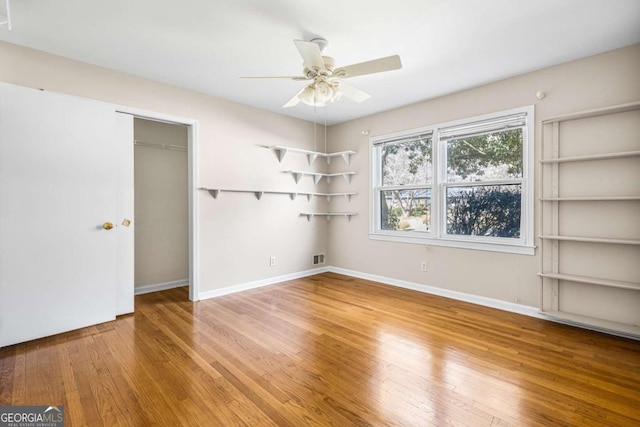 unfurnished bedroom featuring wood finished floors, baseboards, a closet, and ceiling fan