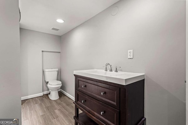 bathroom with visible vents, toilet, wood finished floors, baseboards, and vanity