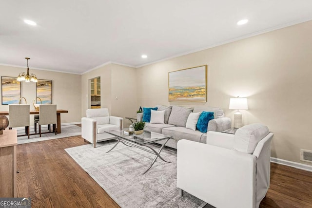 living room featuring dark wood-type flooring, a notable chandelier, crown molding, and baseboards