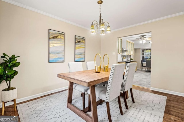 dining room with ceiling fan with notable chandelier, crown molding, wood finished floors, and baseboards