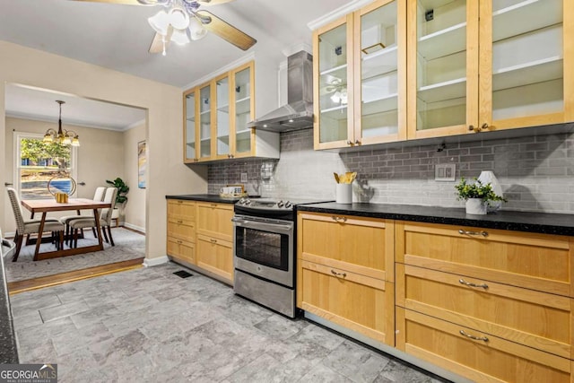 kitchen with decorative backsplash, ceiling fan with notable chandelier, stainless steel range with electric cooktop, wall chimney range hood, and glass insert cabinets