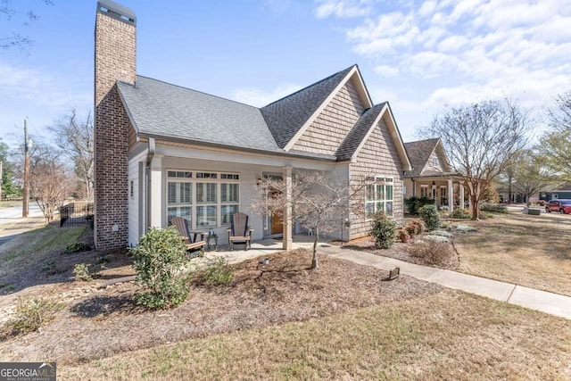 view of front of home featuring a front lawn, a chimney, and a shingled roof