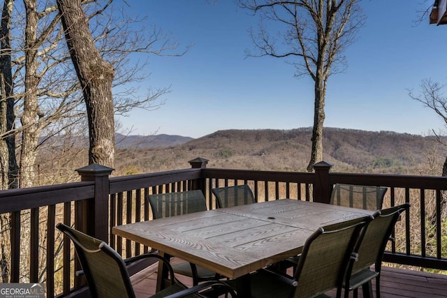 deck with outdoor dining area and a mountain view