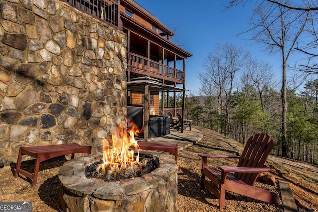 exterior space with a lit fireplace and a balcony