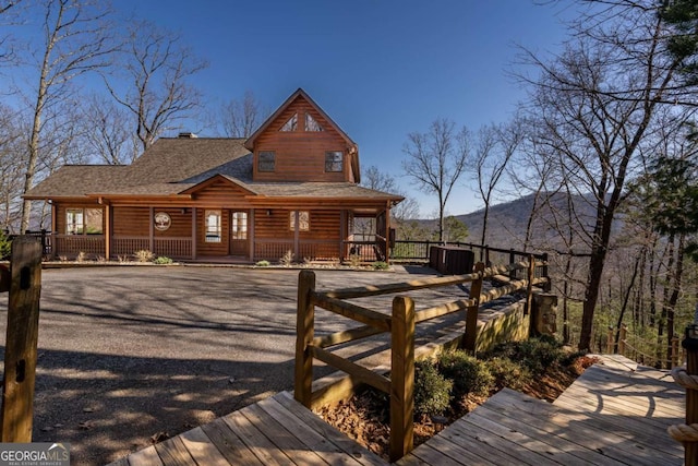 rear view of house featuring covered porch and roof with shingles