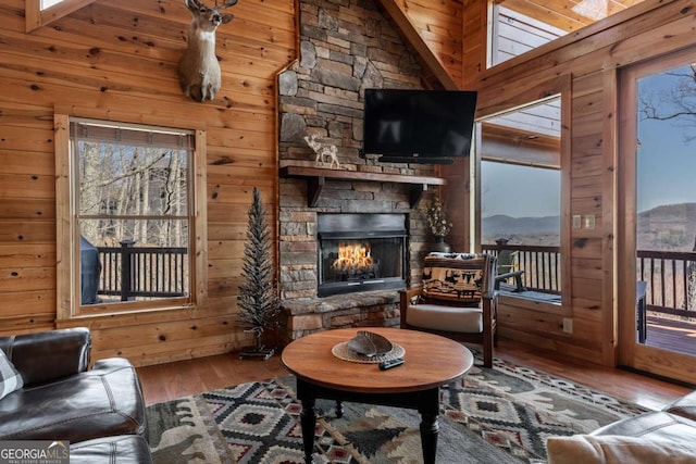 living room featuring a healthy amount of sunlight, wood finished floors, a fireplace, and wood walls