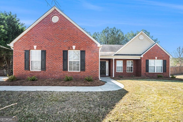 view of front of property with brick siding, a front yard, and fence