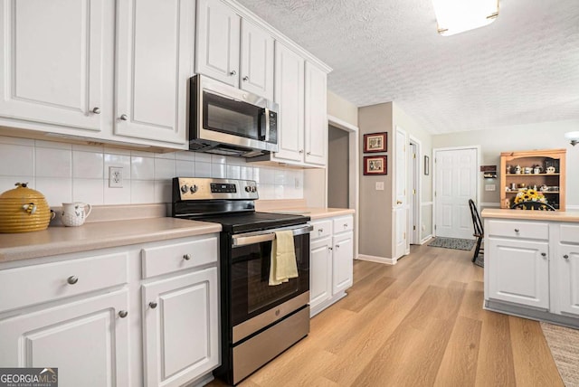 kitchen with white cabinetry, light countertops, light wood-type flooring, and stainless steel appliances