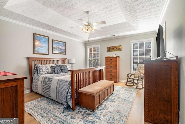 bedroom featuring multiple windows, a textured ceiling, wood finished floors, crown molding, and a raised ceiling