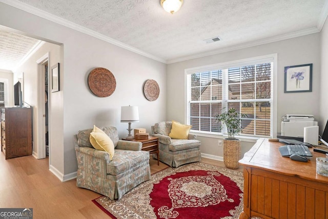 office featuring a textured ceiling, wood finished floors, visible vents, and ornamental molding