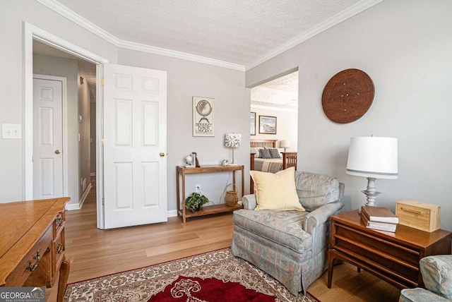 living area featuring light wood-style flooring, a textured ceiling, baseboards, and ornamental molding