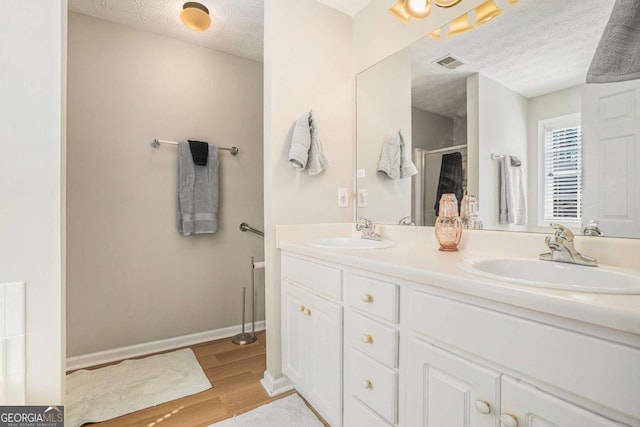 full bathroom with a textured ceiling, wood finished floors, visible vents, and a sink