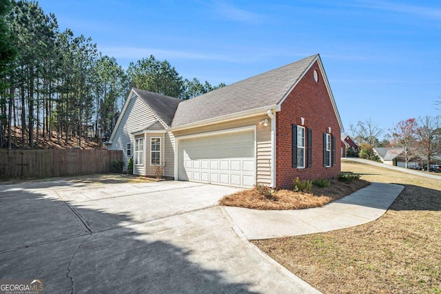 view of property exterior featuring brick siding, concrete driveway, an attached garage, and fence