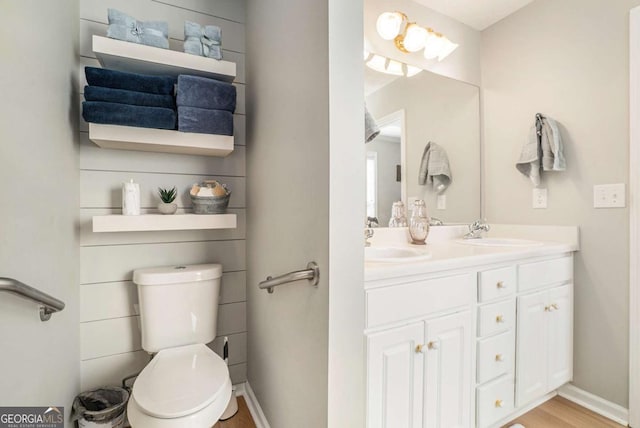 full bath featuring double vanity, toilet, baseboards, and a sink