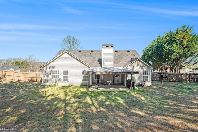 back of house with a yard, a patio area, a fenced backyard, and a chimney