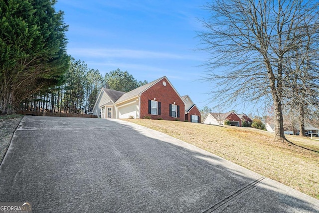 view of front of house featuring driveway, a front lawn, fence, an attached garage, and brick siding