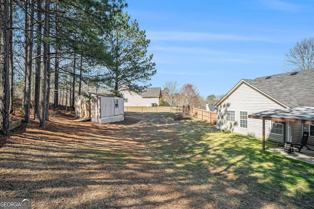 view of yard featuring a storage unit, a fenced backyard, a patio, and an outdoor structure