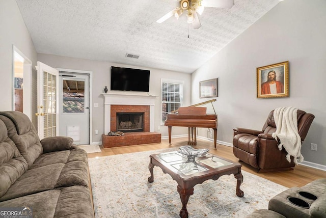 living room featuring lofted ceiling, light wood-type flooring, visible vents, and ceiling fan