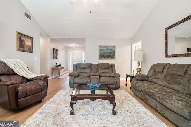 living room featuring visible vents, baseboards, lofted ceiling, light wood-style floors, and a ceiling fan