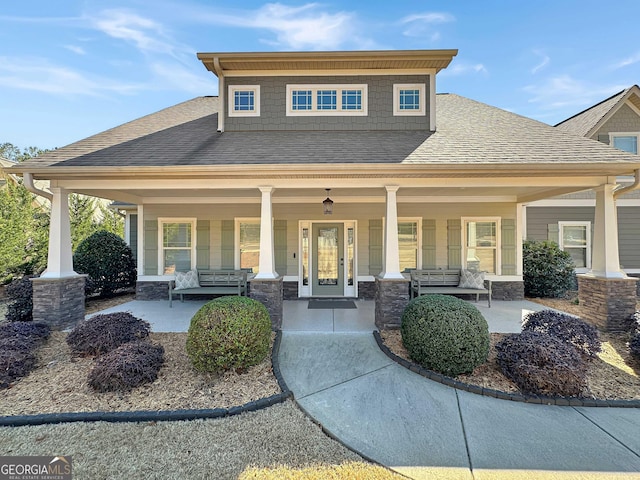 craftsman-style home featuring stone siding, a porch, and a shingled roof