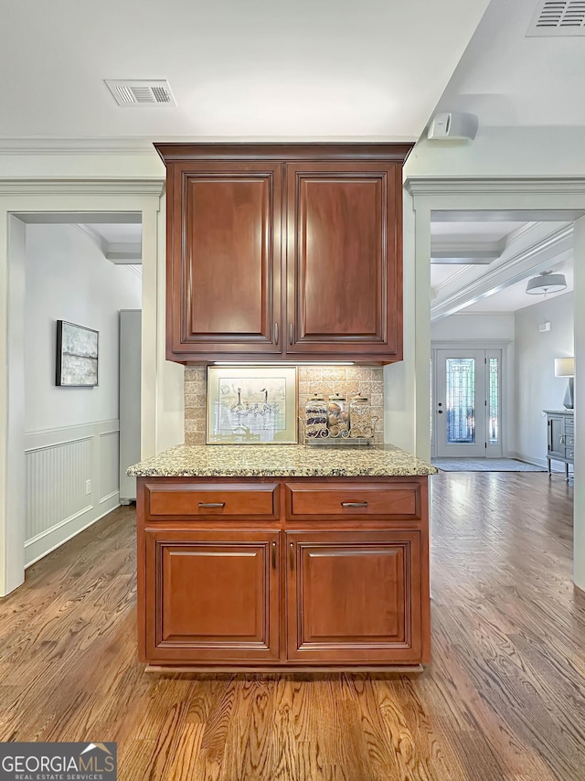 kitchen with tasteful backsplash, visible vents, light stone counters, and light wood-style floors