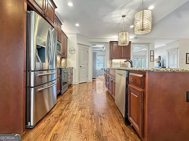 kitchen featuring dark wood-type flooring, recessed lighting, appliances with stainless steel finishes, light stone countertops, and hanging light fixtures