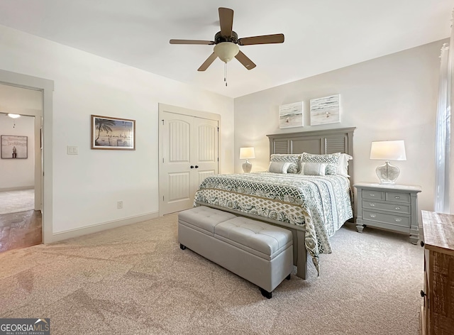 carpeted bedroom with a ceiling fan, a closet, and baseboards