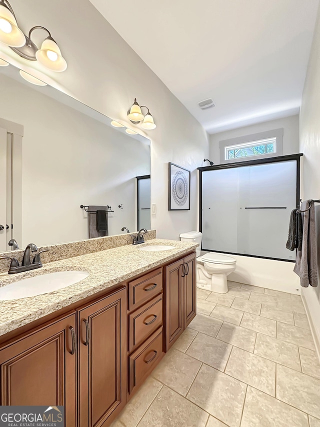 full bathroom with toilet, visible vents, shower / bath combination with glass door, and a sink